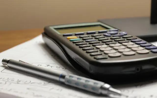 A graphing calculator and mechanical pencil resting on handwritten maths notes